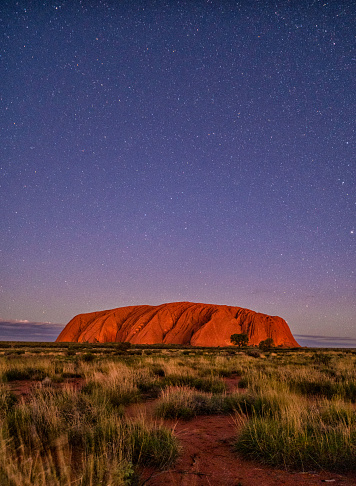 Northern Territory, Australia - March 29, 2016: Uluru lies in the heart of Australia's Outback, here we see it at dusk, reflecting the light from the setting sun. This great mass of sandstone, technically known as an inselberg, is a sacred site to the local Anangu people, and is something of a Mecca for travellers & photographers alike.