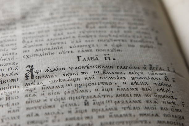 istock Open book with light spotlight on text. Reading of opened book educate reader. Ancient Bible text reading on black background. Russian bible 695845940