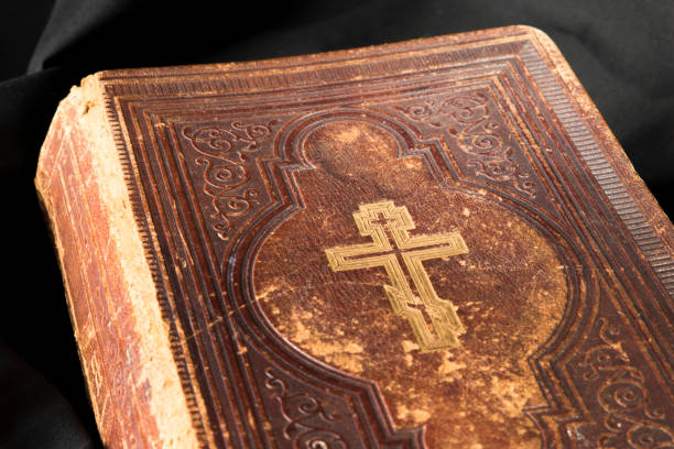 istock Old book on black background. Ancient christian Bible. Close up antique Holy Scripture book. Cross on bible cover. 695845952