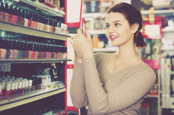 istock Smiling woman customer browsing rows of lipstick 695847184