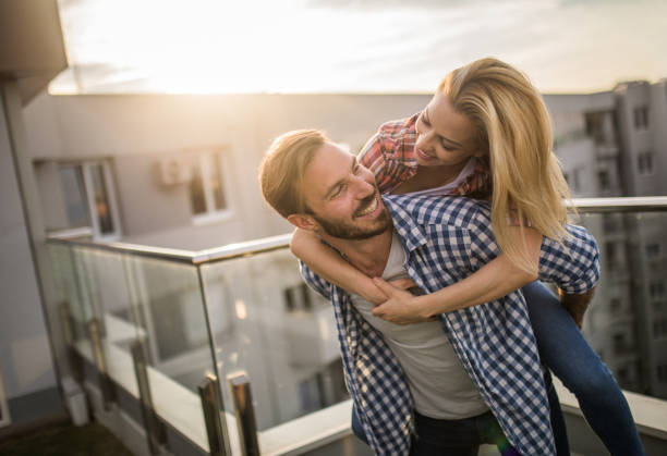 istock Young happy couple having fun while piggybacking on a terrace at sunset. 695851432