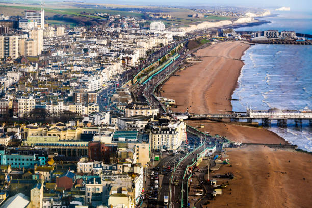 Aerial view of pier and Brighton beach and seafront, Brighton, UK Aerial view of Regency and Victorian architecture of the coastal resort town of Brighton, UK. We can see the piers of Brighton and people walking along the sandy beach and seafront. Houses and traditional victorian architecture recede into the background. Horizontal colour image with copy space. brighton england stock pictures, royalty-free photos & images