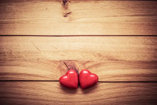 Photo of A couple of red little hearts on wood. Vintage concept of love, Valentine's Day