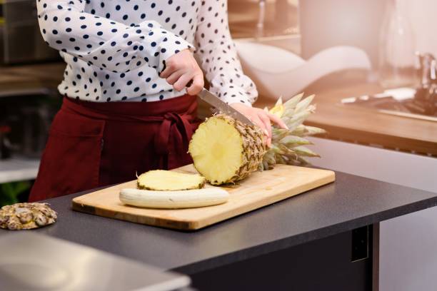 istock Woman, cafe worker slicing pineapple at the cutting board 695854248