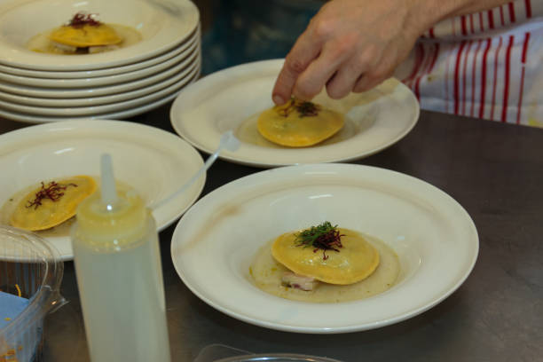 istock Chef Preparing Ravioli Italian Pasta with Red Vegetable with Sauce inside white Dishes 695854416