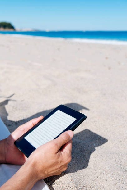 タブレットやビーチで e リーダーで読んで - reading beach e reader men ストックフォトと画像