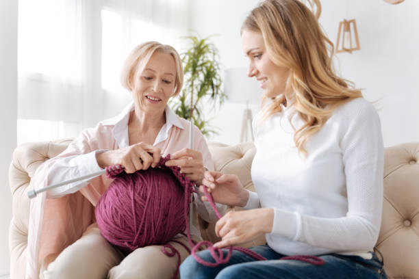 istock Young woman helping her mother with knitting 695854992