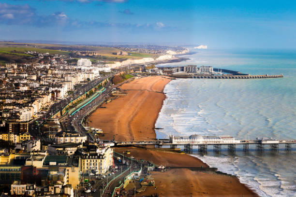 Wide angle aerial view of Brighton beach and coastline, Brighton, UK Wide angle aerial view of the beach and coastal town of Brighton, East Sussex, UK. We can see both piers extending out into the sea and in the distance the white cliffs of Sussex. Horizontal colour image with copy space. east sussex photos stock pictures, royalty-free photos & images