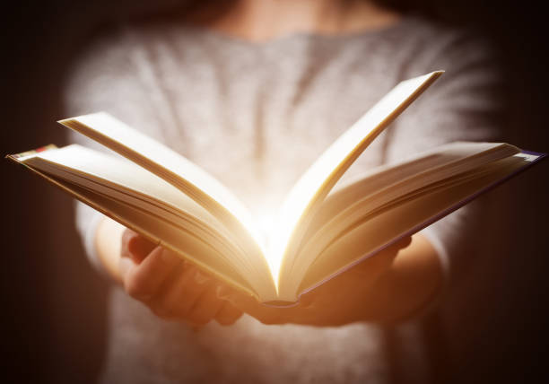 Light coming from book in woman's hands in gesture of giving Light coming from book in woman's hands in gesture of giving, offering. Concept of wisdom, religion, reading, imagination. life lessons stock pictures, royalty-free photos & images