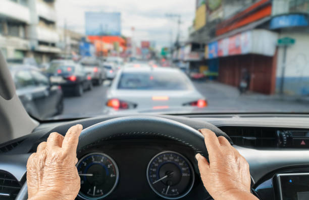 donna anziana alla guida di un'auto in ingorgo - car steering wheel windshield speedometer foto e immagini stock