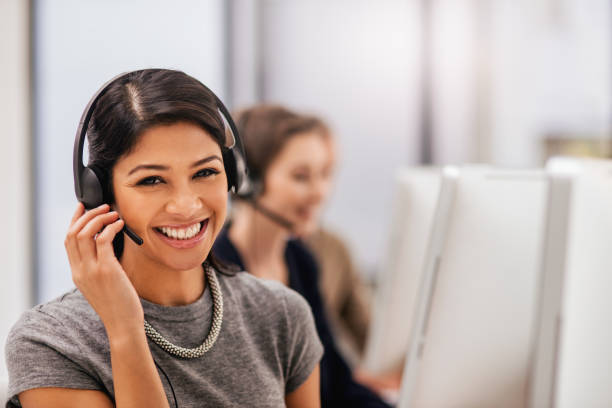 Is there anything else I can help with? Portrait of a call centre agent working in an office with her colleagues in the background answering photos stock pictures, royalty-free photos & images