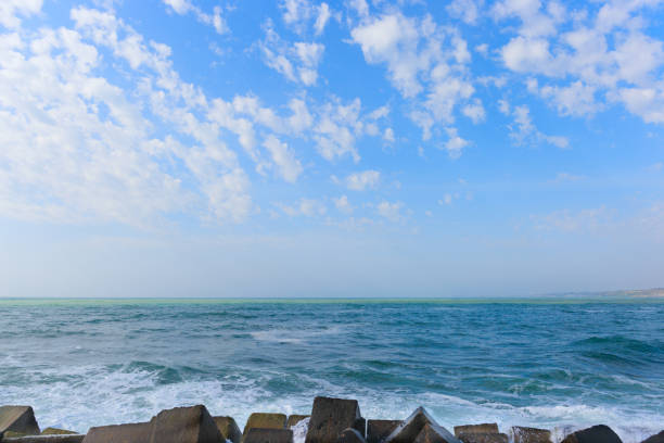 day landscape blue sea with waves ,blue sky with clouds and foreground stones