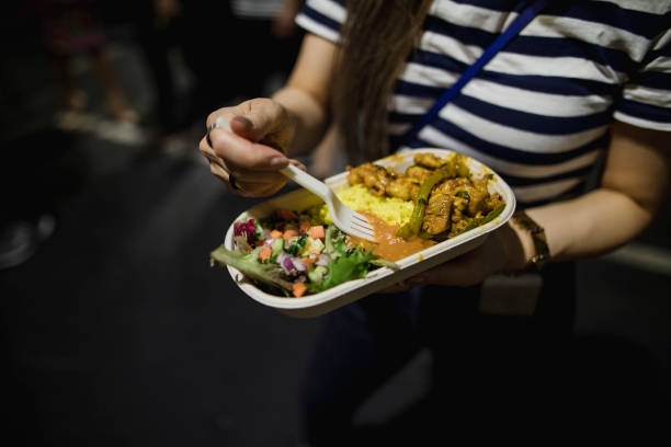 Close up young woman eating food at a night market in Melbourne, Australia.
