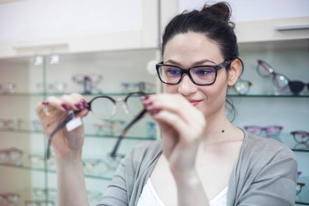 istock Smiling young woman trying on glasses 695885126