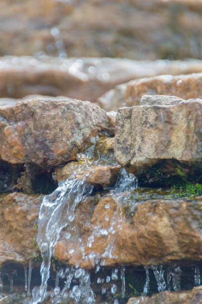 istock at folded the rocks flowing stream of water, closeup 695887894