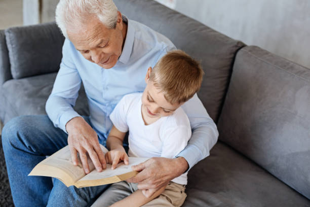 istock Original awesome man teaching his grandson reading 695890200