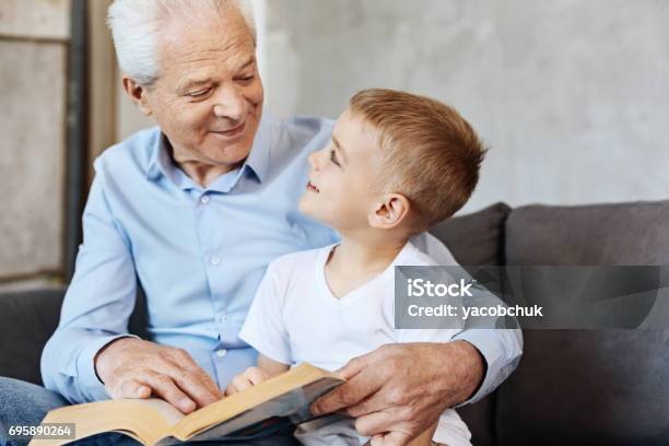 Cute Energetic Kid Enjoying Time With Grandpa Stock Photo - Download Image Now - Grandfather, Reading, Grandson