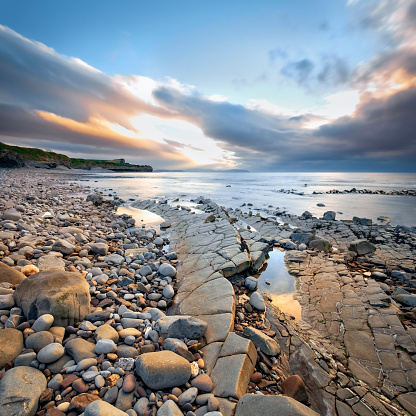 View of pebble Kilve beach at sunset. Copy space in blue sky