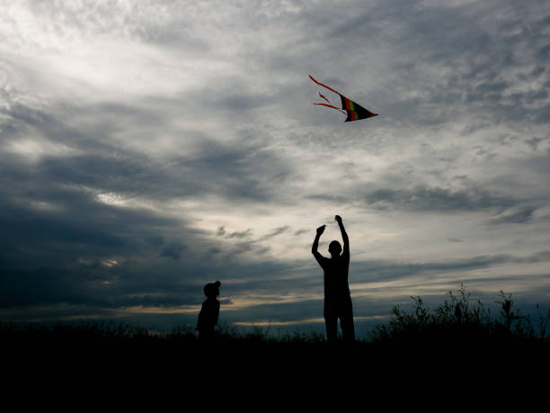 istock father and son flying a kite at sunset 695897126