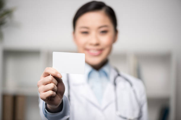 istock selective focus of smiling doctor showing blank card in hand 695900940