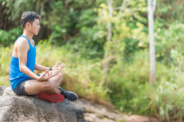 istock Young asian man in a yoga pose at the waterfall 695901448
