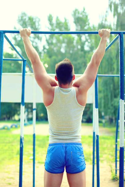 istock Sport, street workout concept - athlete doing pull ups on the horizontal bar outdoors 695904060