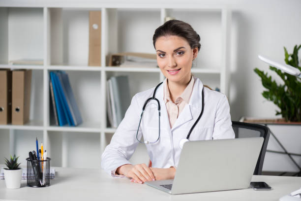 istock young caucasian doctor using laptop and looking at camera in clinic 695904272