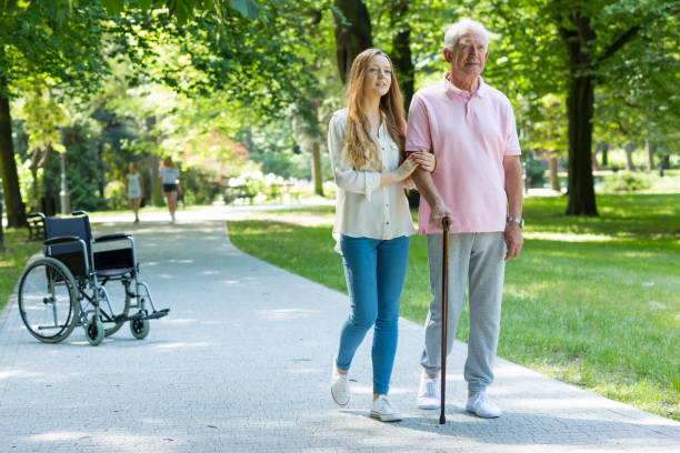 Woman helping elderly man with cane Young woman helping elderly man with walking with cane in the park united states senate committee on health education labor and pensions stock pictures, royalty-free photos & images