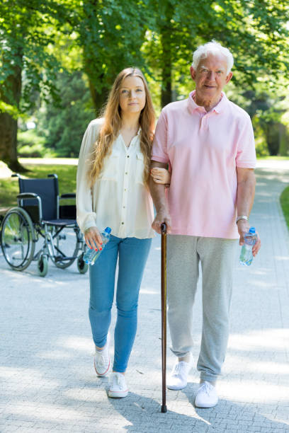 Elder man walking in the park with carer Elder man with a cane walking in the park with his female carer united states senate committee on health education labor and pensions stock pictures, royalty-free photos & images