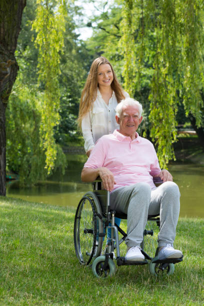Woman with elderly man on a wheelchair Young woman with elderly man on a wheelchair in the park united states senate committee on health education labor and pensions stock pictures, royalty-free photos & images
