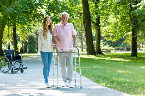 istock Senior man with walking frame accompanied by caregiver 695914830