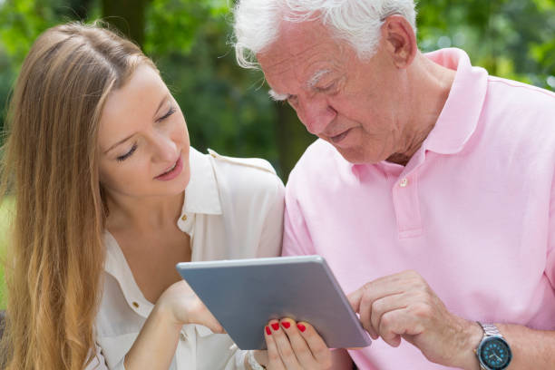 Senior man using a tablet with young girl Closer shot of senior man using a tablet with a help from young girl united states senate committee on health education labor and pensions stock pictures, royalty-free photos & images