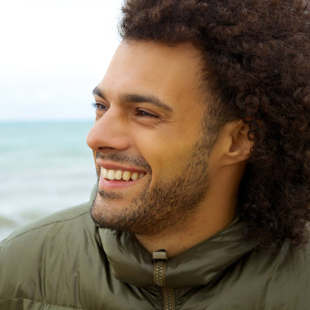 istock Handsome smiling man in winter in front of ocean closeup 695914938