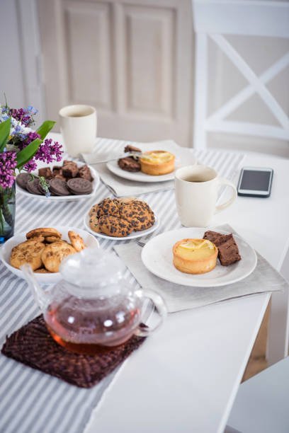 istock tea and various pastry with smartphone lilac flowers on tabletop 695914982