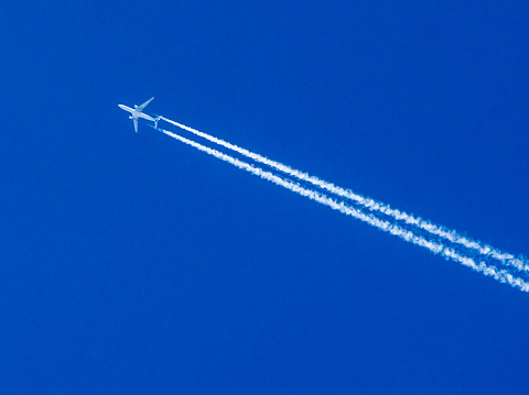 Airplane flying through clear blue sky with vapor trails