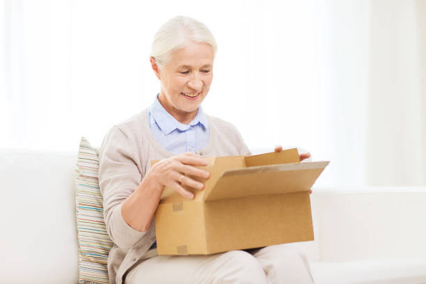 istock happy senior woman with parcel box at home 695917010