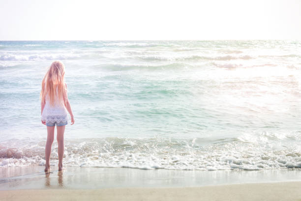 istock Young blonde girl standing on the beach 695920416