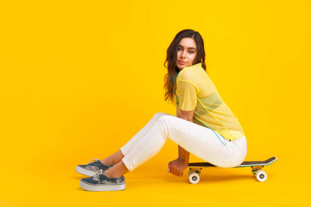 istock Young woman sitting on skateboard 695920750