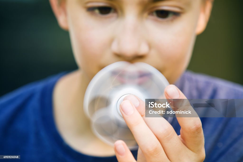 Boy Holding Spinner A 13 year old boy holding a spinner close to his face. Attention Deficit Hyperactivity Disorder Stock Photo