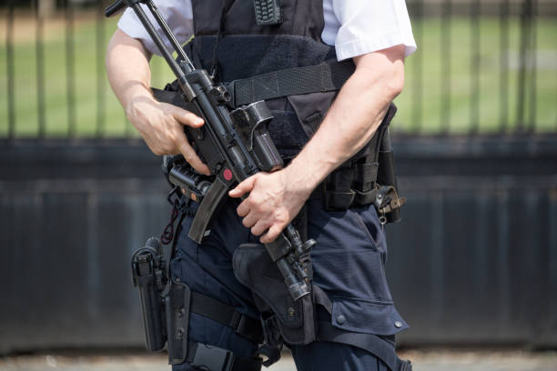 Armed policeman standing guard outside the Houses of Parliament, Westminster, London England stock photo