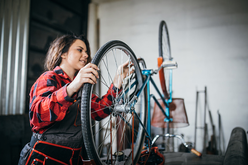 Woman repairing bicycle in workshop