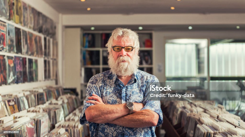 Record store owner portrait Horizontal color portrait of a senior record store owner in his shop. Owner Stock Photo