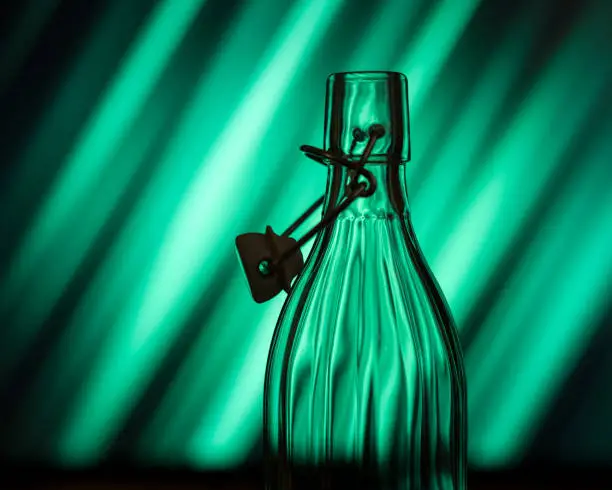 Open glass bottle in front of a creative background