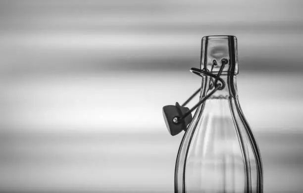 Open glass bottle in front of a creative black and white background