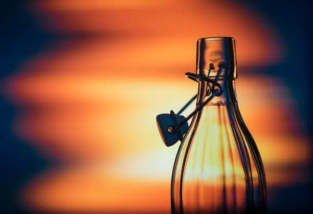 Open glass bottle in front of a creative background