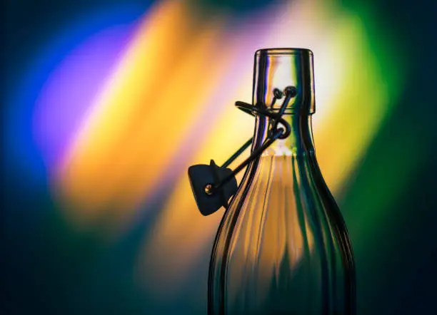 Open glass bottle in front of a creative background