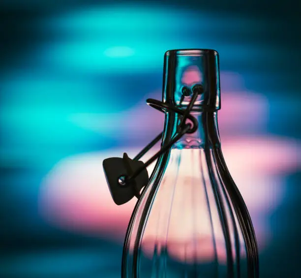 Open glass bottle in front of a creative background