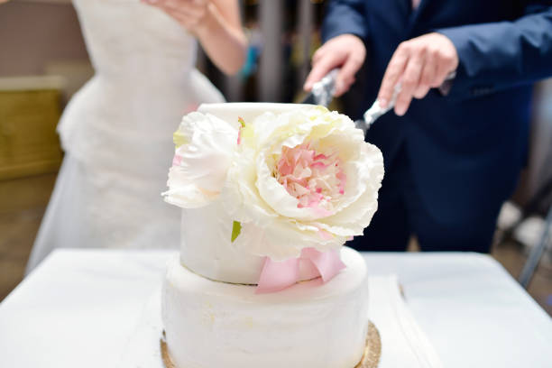 istock Beauty bride and handsome groom are cutting a wedding cake 695943446