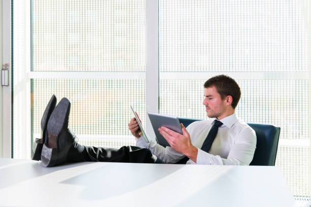 istock Businessman relaxing...siting with his feet on a table,playing with digital tablet 695959834