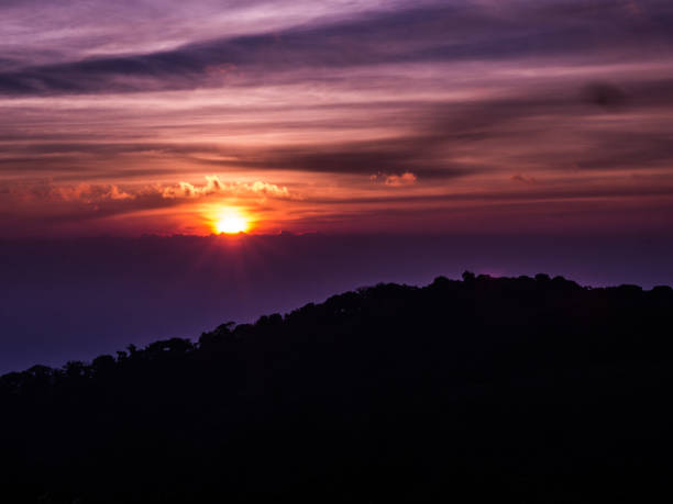 istock The sun rises behind the horizontal cloud with the shadow of the mountain in front. 695962034